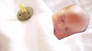 Neugeborener schlafender Junge mit Schnuller
