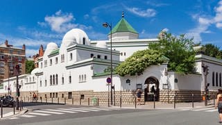 Paris, France - June 07, 2018: Eastern side of the Great Mosque of Paris with the entrance of the tea room and restaurant, the dome of the prayer hall with green tiles and the top of the minaret. 