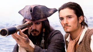 Johnny Depp schaut als Captain Jack Sparrow durch ein Fernglas. Neben ihm Orlando Bloom.