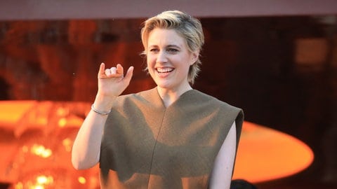 Greta Gerwig winkt an einer Balustrade