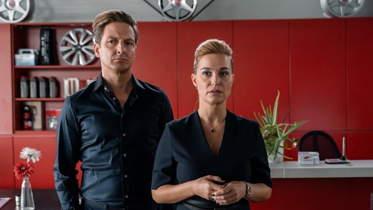 "Alles gelogen": Im Büro des Autohauses: Kirsten (Pina Kühr) und Alexander Ludwig (Holger Stockhaus) stehen mit traurigem Blick nebeneinander.