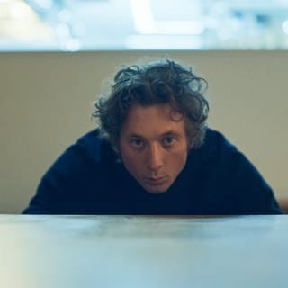 Carmy (Jeremy Allen White) blickt prüfend über die Kante eines Tisches.