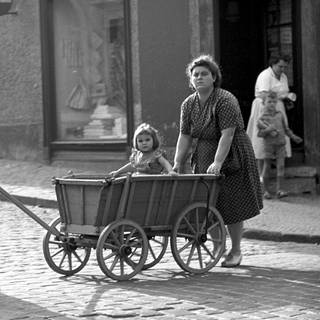 Frauen aus drei Generationen gehen mit einem Handwagen spazieren (1960).