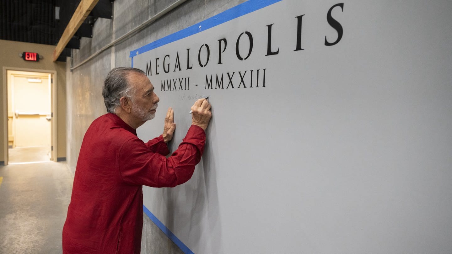 Francis Ford Coppola schreibt etwas an die Wand, auf der Megalopolis steht