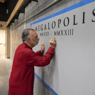 Francis Ford Coppola schreibt etwas an die Wand, auf der Megalopolis steht