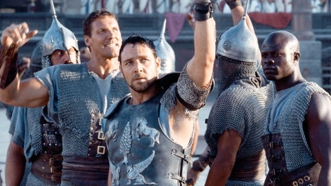 Russell Crowe als Maximus Decimus Meridius inmitten einer Schar feiernder Gladiatoren in der Arena (Filmszene „Gladiator, 2000)