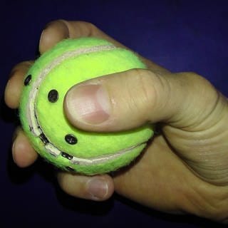eine Hand mit einem präparierten Tennisball