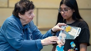 Die Holocaustüberlebende Inge Auerbacher zeigt einer Schülerin, wie der Davidstern auf der Kleidung getragen werden musste