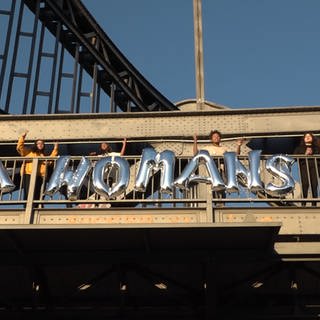 Schrift aus Luftballons an einer Brücke: "A Woman's Work"