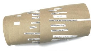 Eine Papierrolle mit ausgeschnittenen Satzfragmenten - die sogenannte Metamaschine
