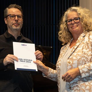 Karl-Sczuka-Preisverleihung 2022: Anke Mai übergibt die Urkunde an Jan Jelinek