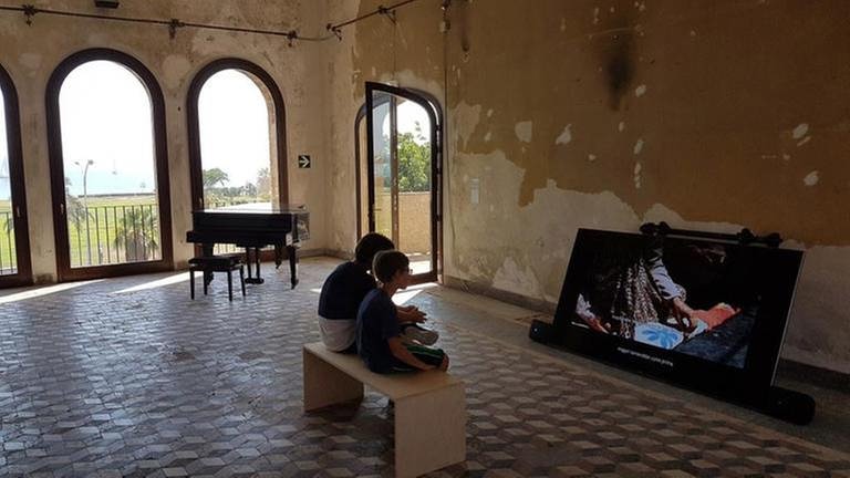 Zwei Kinder vor einem Bildschirm im verfallenden Palazzo Forcella de Seta