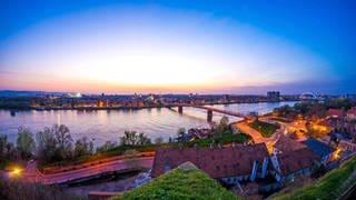Als Brückenbauer sieht Novi Sad, die Hauptstadt der serbischen Vojvodina, seine Rolle als europäische Kulturhauptstadt. Der EU-Beitrittskandidat setzt auf große Events: Blick in der Dämmerung auf die Donau, Brücke und Stadt Novi Sad.