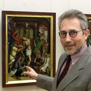 Klaus Schrenk, Staatlichen Kunsthalle Karlsruhe, zeigt auf die Tafel "Geißelung Christi"