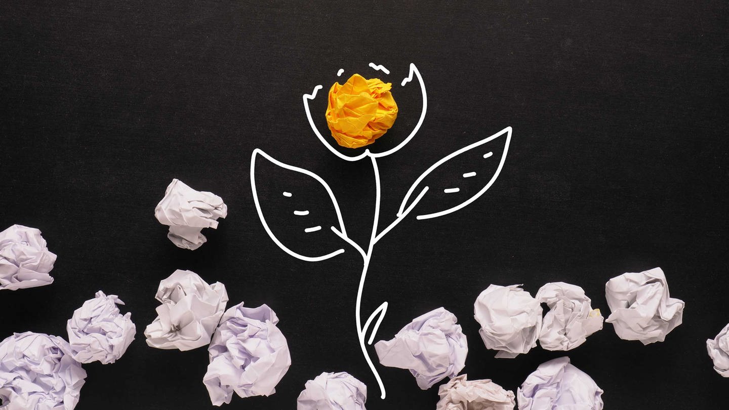 Papierknäuel auf einer gezeichneten Pflanzenblüte (Zeichnung ist mit weißen Konturen auf schwarzes Papier gezeichnet.)