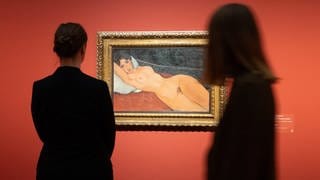 Zwei Frauen stehen während eines Pressetermins vor dem Gemälde "Liegender Frauenakt mit weißem Kissen" aus dem Jahr 1917 von Amedeo Modigliani.