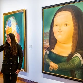 Eine Frau macht ein Selfie vor einer Karikatur der Mona Lisa 