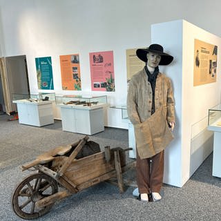 Blick in die Ausstellung 2_Originales Kostüm des Jakob aus DIE ANDERE HEIMAT von Edgar Reitz_Schubkarre Ende