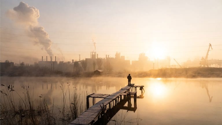 Ein Mann steht auf einem Steg und fischt in der Nähe des Asowstal-Werks im Fluss Kalmius in der Nähe des Asowschen Meeres