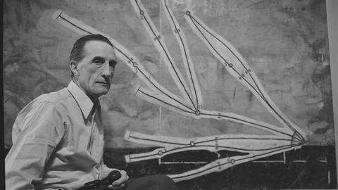 Der Dadaist Marcel Duchamp vor einem seiner Kunstwerke (Schwarz-weiß-Aufnahme von 1952)
