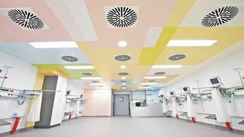 Bunte, symmetrisch angeordnete Flächen an der Decke im Aufwachraum eines Krankenhauses.