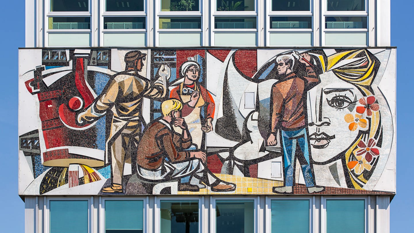 Wandfries des Künstlers Walter Womacka an der Fassade des Haus des Lehrers in Berlin: Darauf sind stilisierte Personen in bunten Farben zu sehen