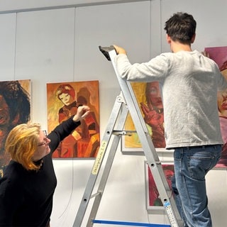 Lehrerin Anne-Katrin Dietrich und Schüler Farin Göbel beim Hängen von Bildern für die Ausstellung „Onirique“ im Landeskunstgymnasium Alzey.