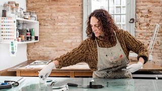 Eine Künstlerin bereitet einen Kunst-Druck in ihrem Atelier vor 