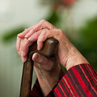 Hände einer alten Frau auf einem Gehstock
