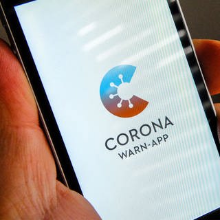 Auf dem Bildschirm eines iPhones ist der Startbildschirm einer Corona Warn-App abgebildet