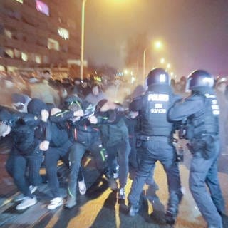 Eine Menschengruppe durchbricht eine Polizeiabsperrung 
