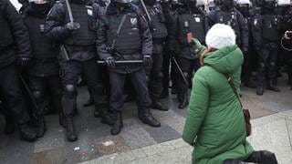 Russland 2021: Eine Frau kniet während einer nicht autorisierten Kundgebung  vor Bereitschaftspolizisten auf dem Puschkinskaja-Platz