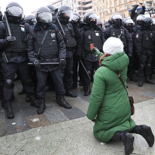 Russland 2021: Eine Frau kniet während einer nicht autorisierten Kundgebung  vor Bereitschaftspolizisten auf dem Puschkinskaja-Platz