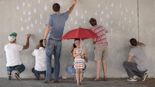 Menschen zeichnen Regentropfen auf eine Betonwand