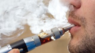  Ein Mann raucht eine elektrische Zigarette, die viel Dampf erzeugt