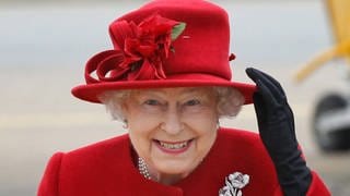 Queen Elizabeth II holds on to her hat in high winds during a visit to RAF Valley