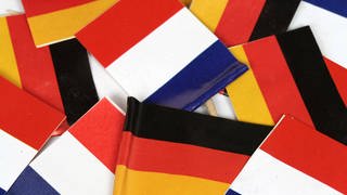 Flaggen der Republik Frankreich und Bundesrepublik Deutschland liegen auf einem Stapel