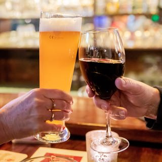 Zwei Gäste stoßen in einer Berliner Gaststätte mit Wein und Bier an.