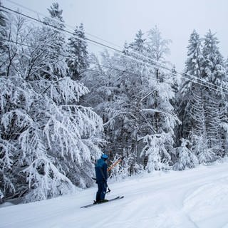 Ein Skifahrer lässt sich mit einem Bügellift am Wiedener Eck eine Skipiste hinaufziehen