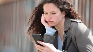 Bored woman checking smart phone in the street