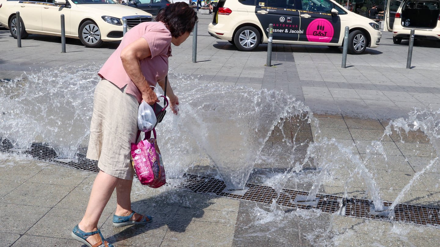 Eine Passantin kühlt sich am Brunnen vor dem Hauptbahnhof Hannover ab