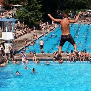 Ein Junge springt in einem Freibad von einem Sprungturm