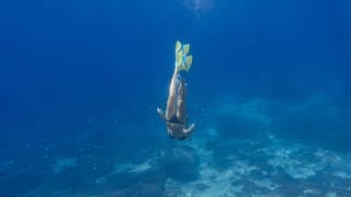 Woman with fins and snorkel diving under water  Symbolfoto