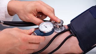 Arzt beim Blutdruck messen. Menschen ohne Krankenversicherung haben in Deutschland nur wenig Anlaufstellen