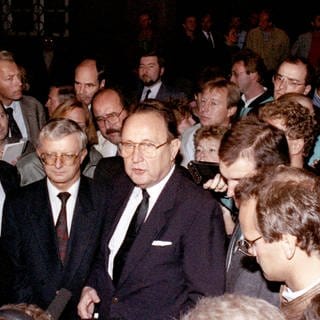 Außenminister Hans-Dietrich Genscher (rechts) und der Kanzleramtsminister Rudolf Seiters (links) von Reportern in der deutschen Botschaft in Prag umgeben