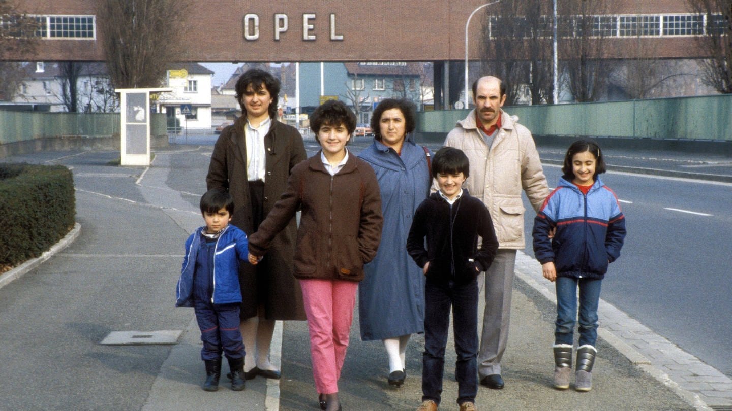 Türkische Gastarbeiterfamilie vor dem Tor der Opel-Werke in Rüsselsheim