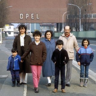 Türkische Gastarbeiterfamilie vor dem Tor der Opel-Werke in Rüsselsheim