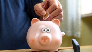 Ein alter Mann wirft Euro Geldmünzen in ein Sparschwein. Altersvorsorge Konzept