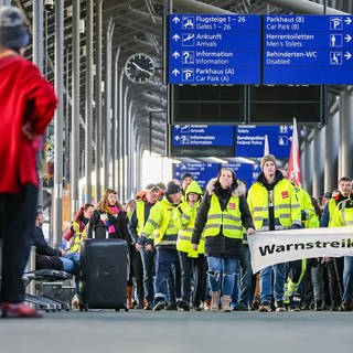 Beschäftigte der Mitteldeutschen Flughafen AG gehen während eines Warnstreiks durch den Flughafen LeipzigHalle. Die Gewerkschaft Verdi hat die Belegschaften der privaten Sicherheitsunternehmen an elf Flughäfen zu einem ganztägigen Warnstreik aufgerufen