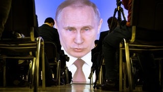 Journalisten verfolgen die Rede von Wladimir Putin, Präsident von Russland, zur Lage der Nation auf einer Videoleinwand.